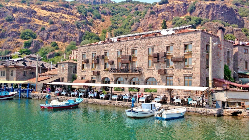 Boats docked by seaside restaurant in Assos Greece.