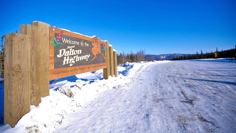 Close up of James Dalton Highway sign surrounded by snow.