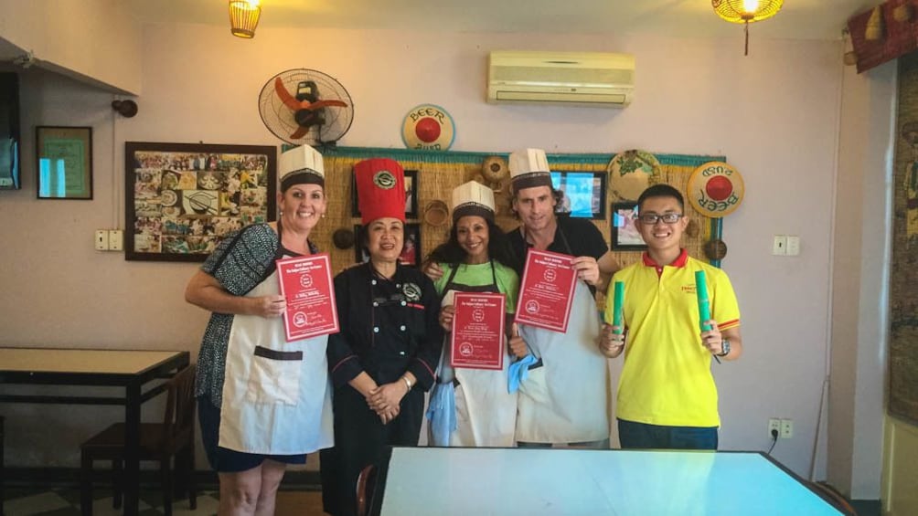 Group members posing with certificates of completion of cooking class.