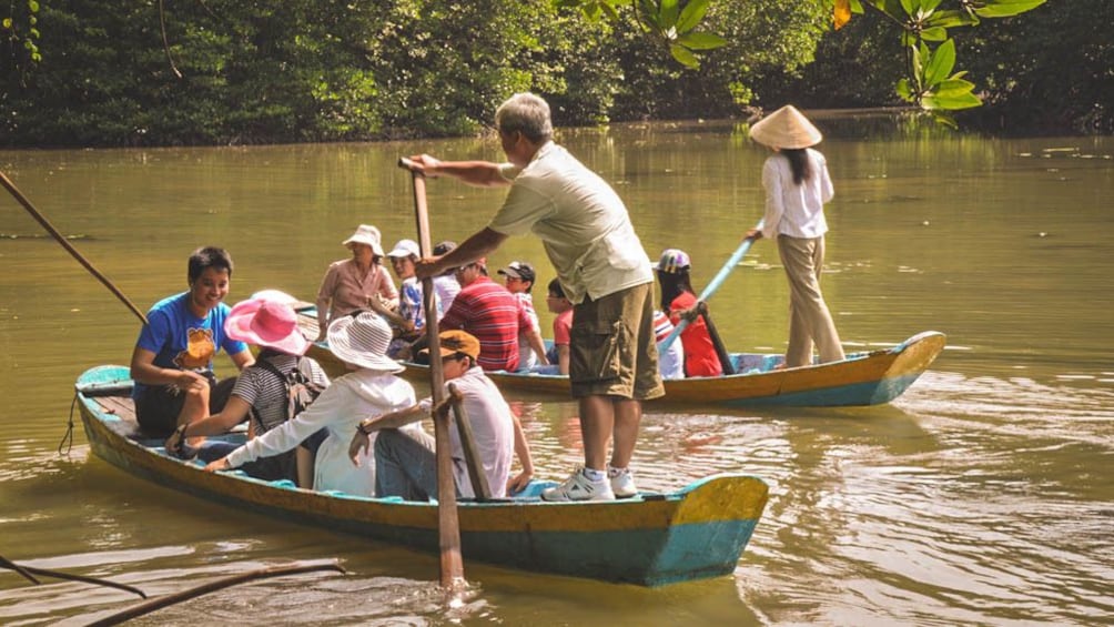 Tour group on small boats in river, with tour guides.