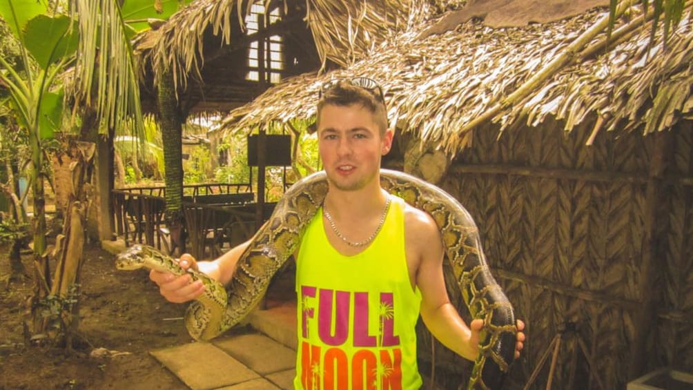 Tourist with giant snake over his shoulders.