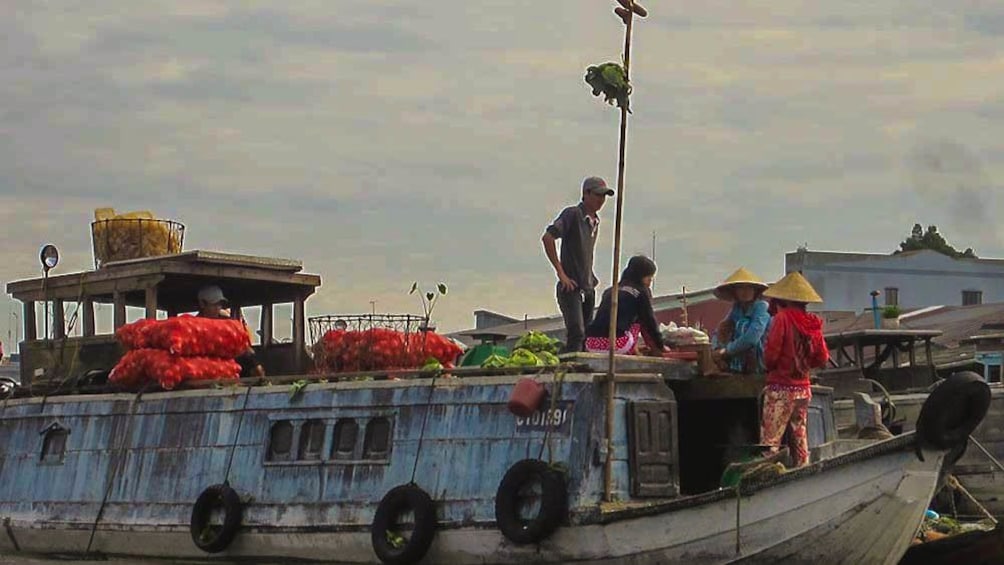 View of boats in river during cloudy day with fresh produce loaded on them.