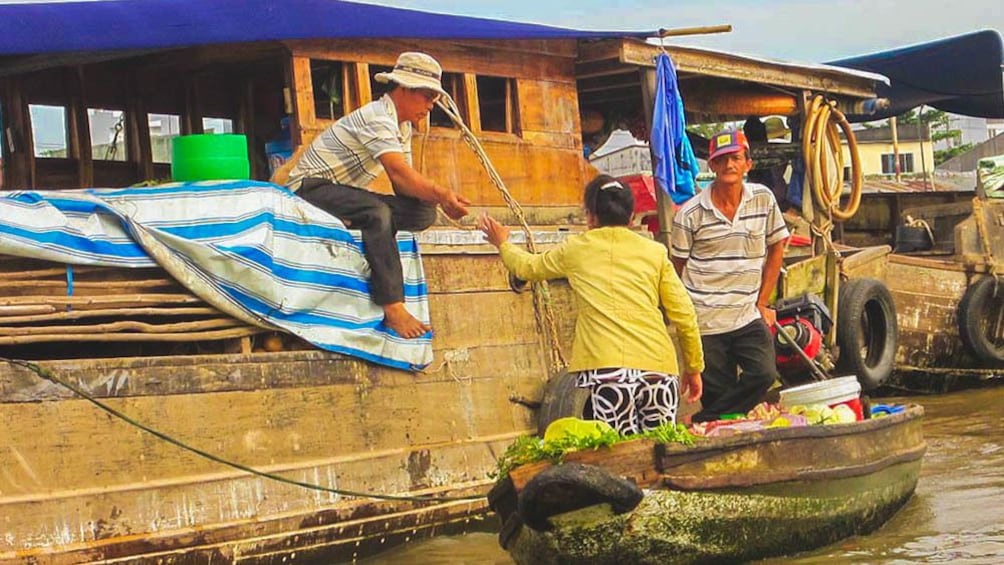 Woman buying fresh produce from boat market.