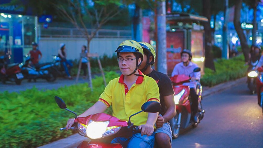 Tour group riding mopeds through the city at night.