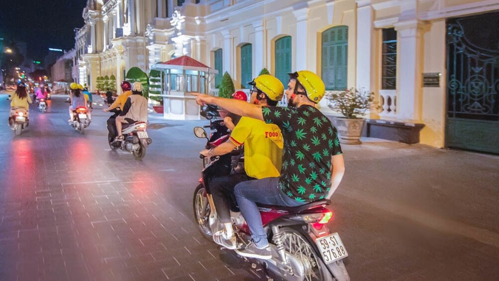 Activity group driving through the street on motor bikes at night.