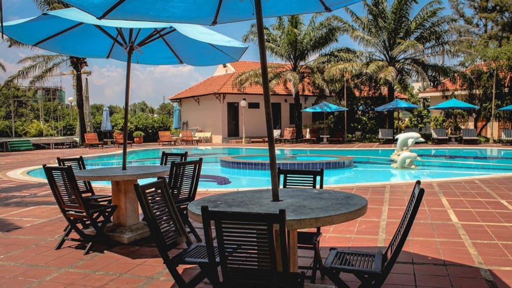 Patio table with umbrellas by swimming pool during the day.