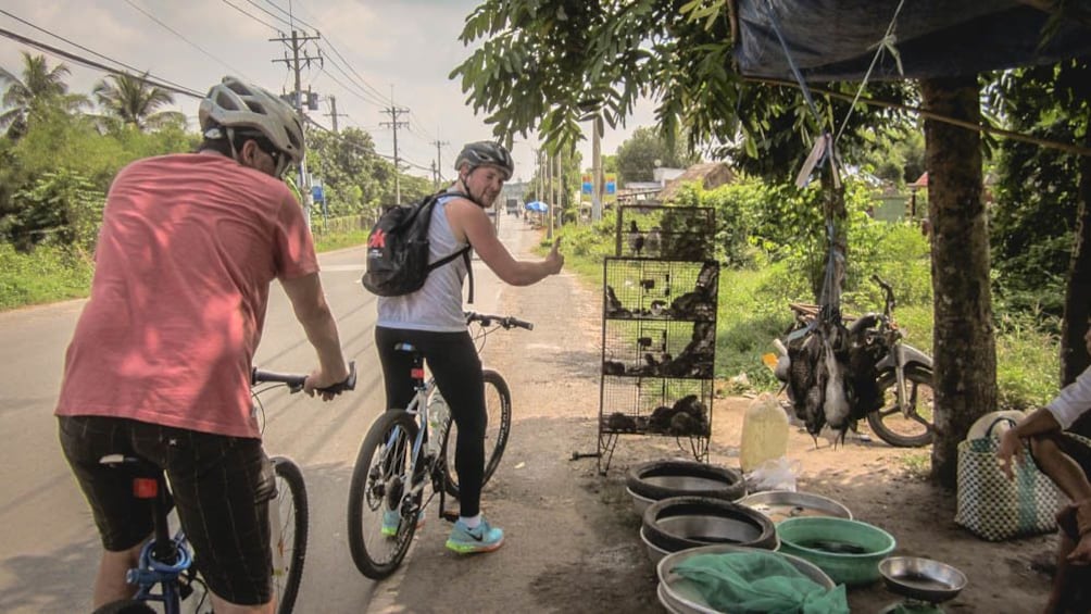 Two male cyclists riding behind one another down street.