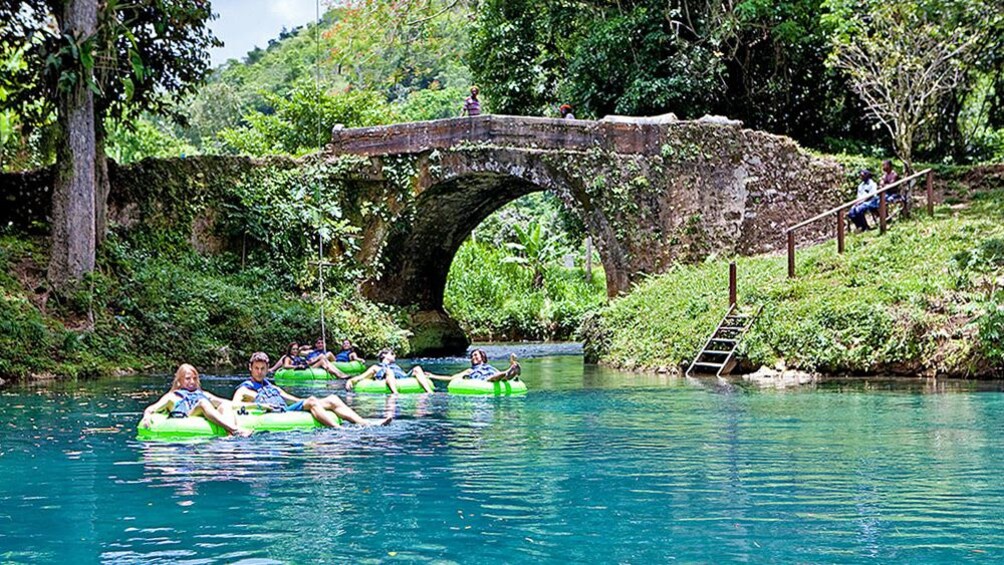 Several people moving down river on floats with beautiful landscape view in the distance.