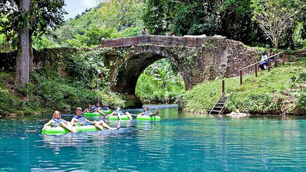 Several people moving down river on floats with beautiful landscape view in the distance.