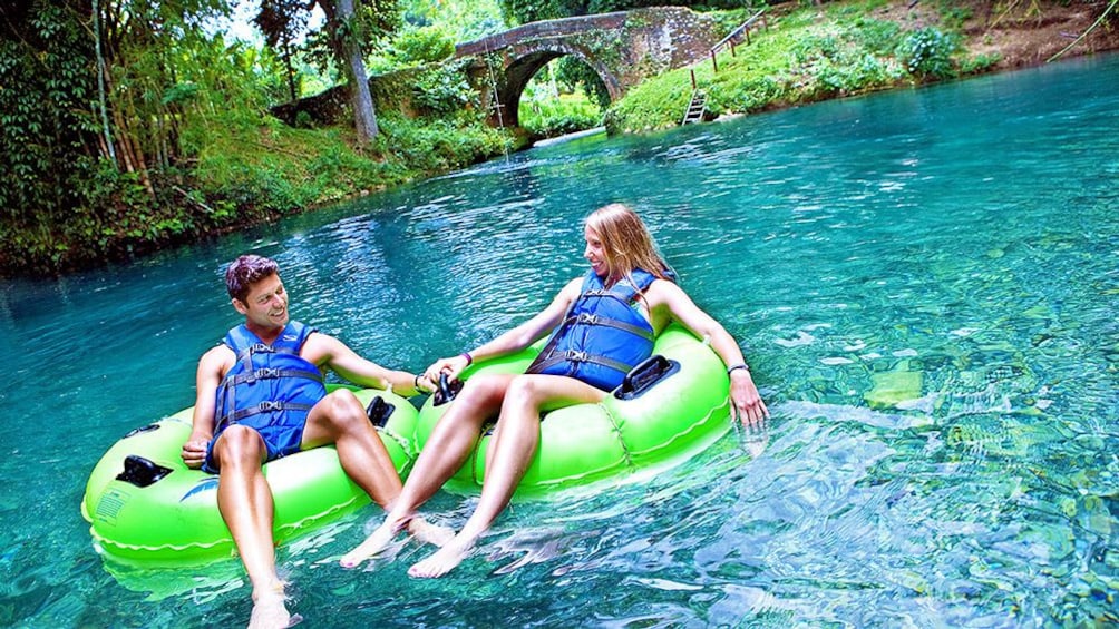 Couple on green floats holding hands in water.