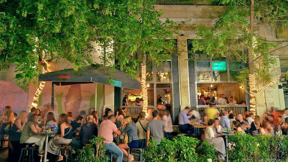 View of restaurant with several people eating outdoors.