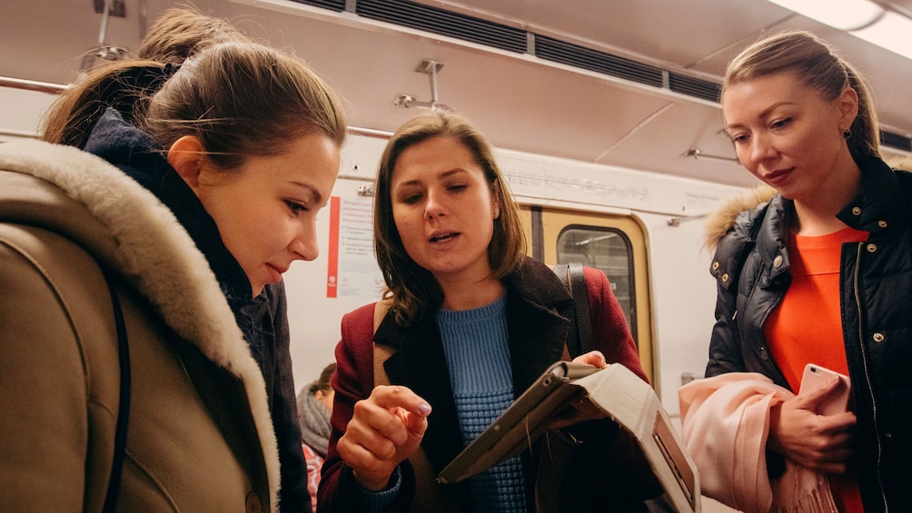 Show item 4 of 5. Three women looking at travel plans