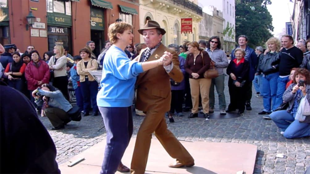 Two people dance in the street, surrounded by onlookers during Mataderos Fair Tour