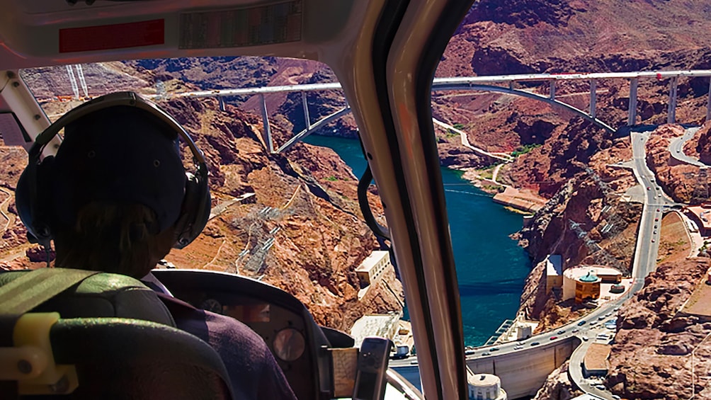 Pilot's view looking through windshield of helicopter down to Hoover Dam