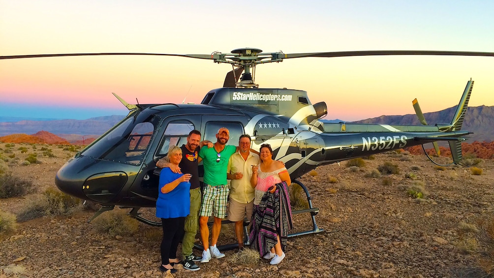 Group of passengers gather outside of helicopter on the edge of the Grand Canyon