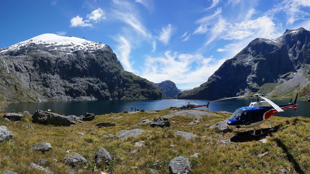 Helicopter landed near water and mountains.