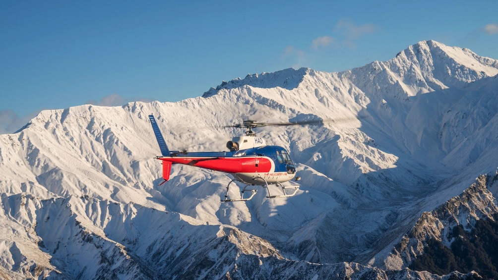 Helicopter flying past mountains in New Zealand