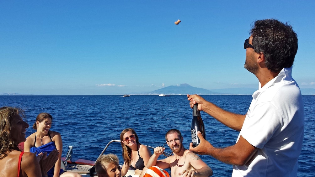 man pops a corked bottle on a boat in Italy
