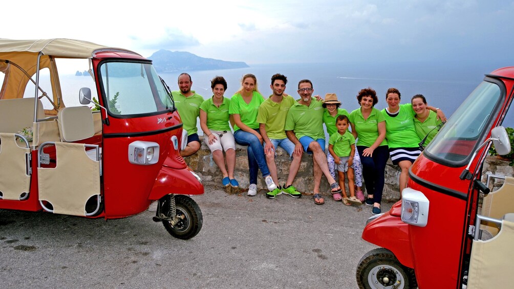 A tourist group posing at a scenic view with scooters