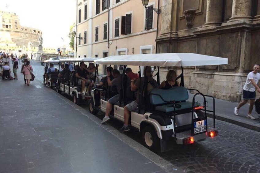 Golf carts touring in a motorcade to accommodate a large group.