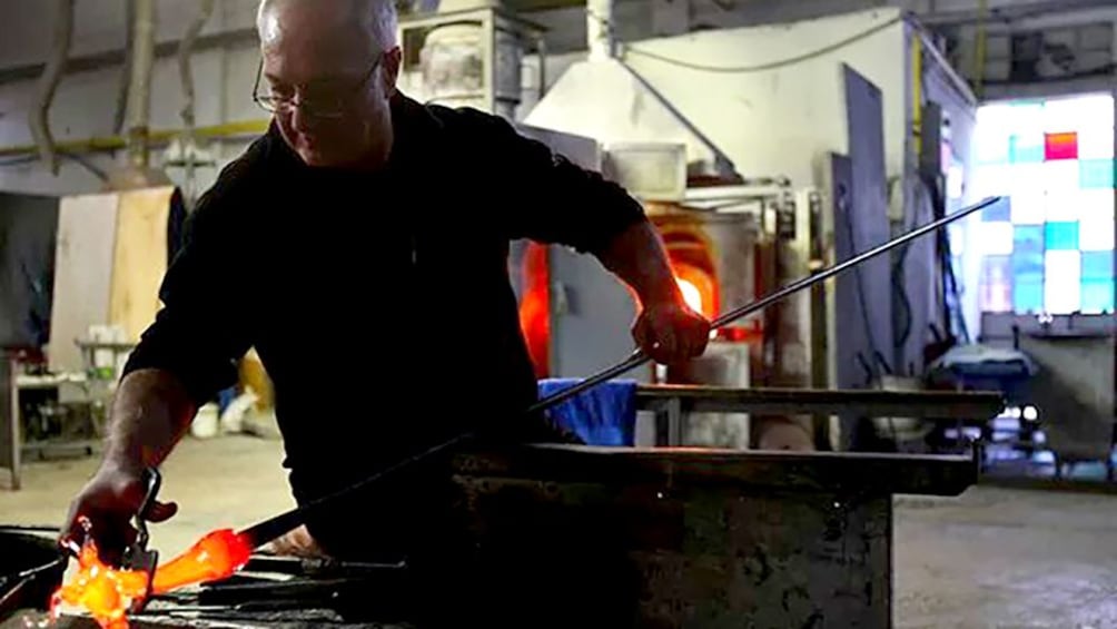 Glass blower sculpts molten glass in his shop