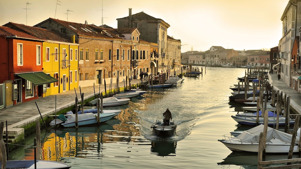 Colorful buildings line a canal at sunset in Murano
