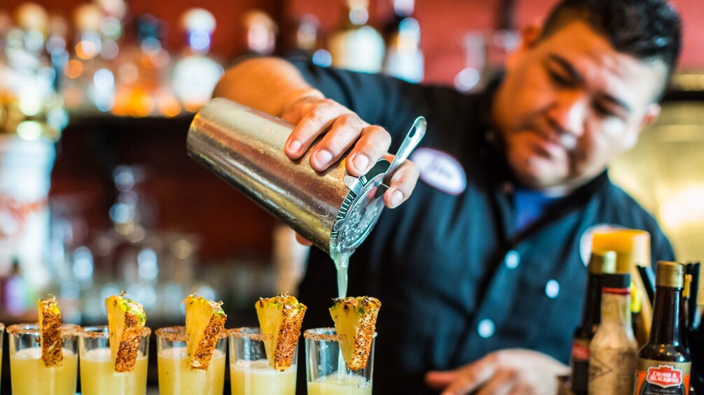 Show item 1 of 6. Bartender pouring cocktails at a bar in Puerto Vallarta