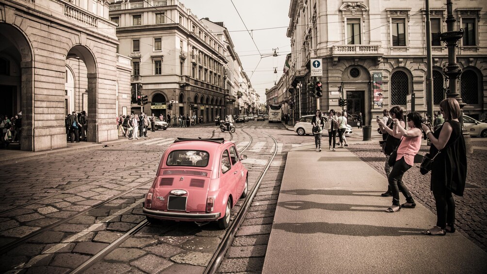 pedestrians taking pictures of a Fiat vehicle on the road in Italy