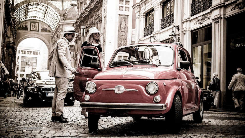 couple in formal clothes entering a small Fiat vehicle in Italy