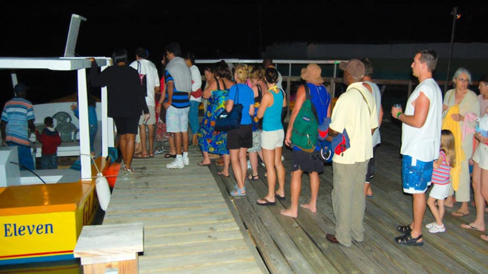 Angled view of people boarding tour boats at night.