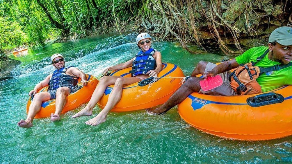 Three people on inner tubes  floating down a river