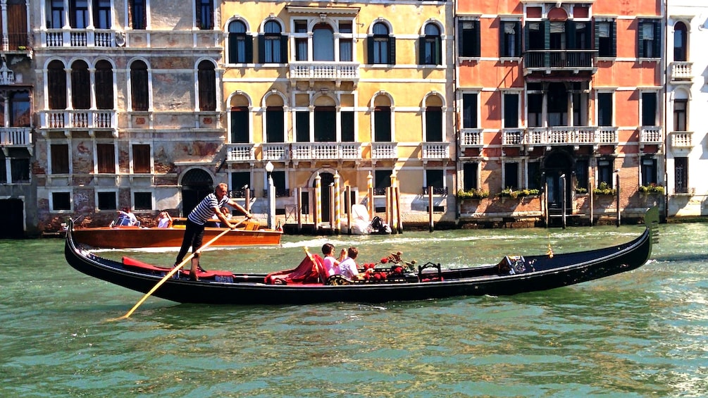 Gondola with patrons traversing through a canal in Venice