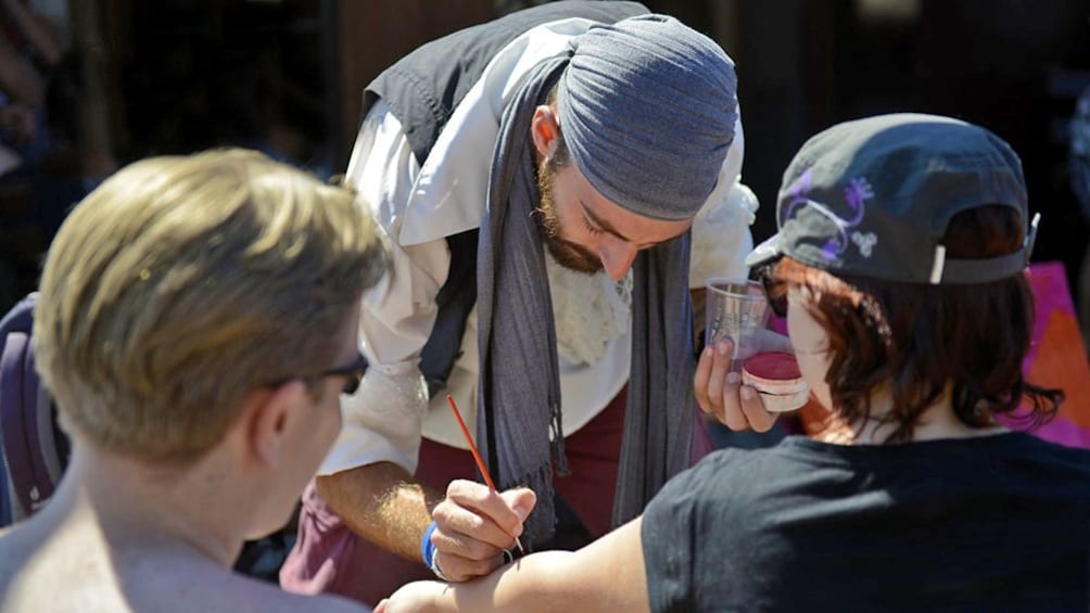 man painting visitor's arms in Greece