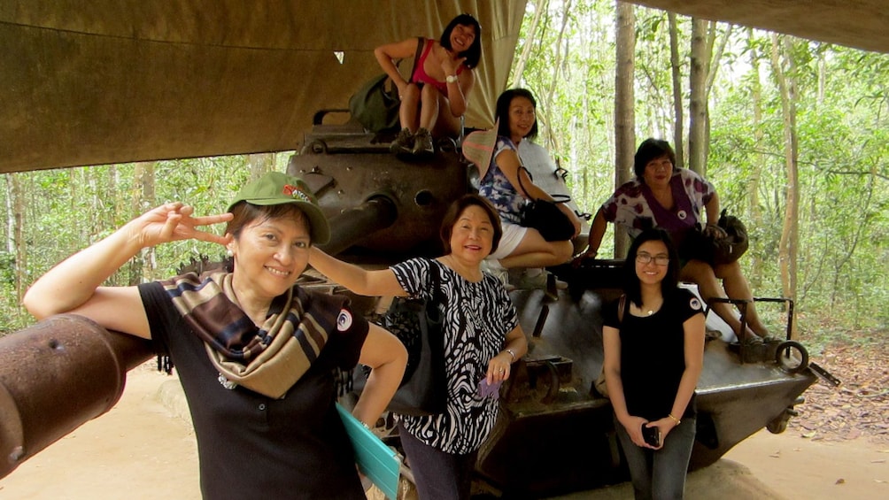 Six women pose on a decommissioned Tank under a canopy in Ho Chi Minh City
