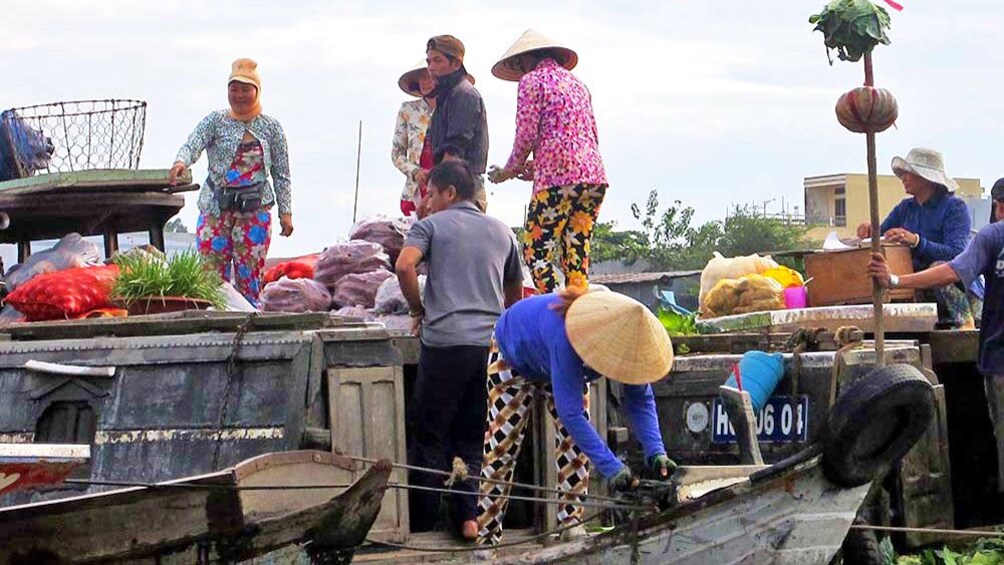 A woman ties a boat to a dockside market in the Mekong Delta
