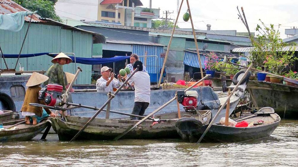 A man purchasing melons from a boat on the Mekong Delta river