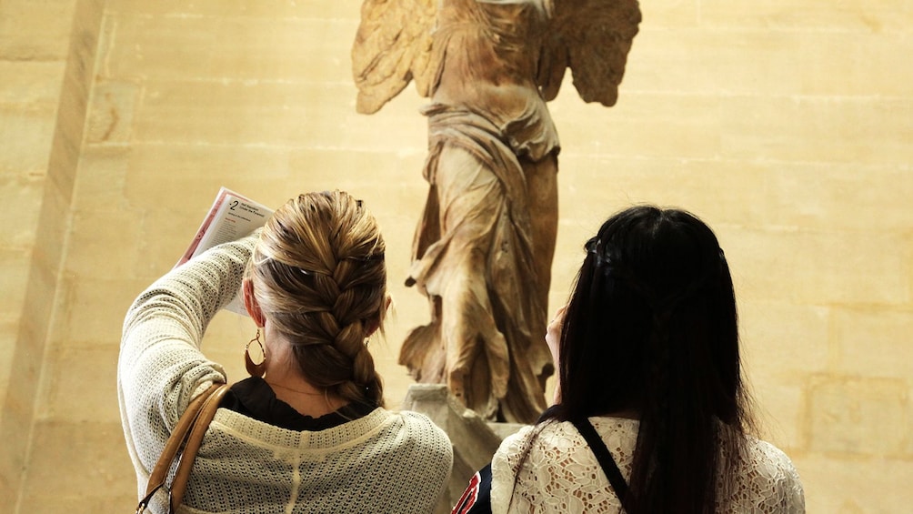 Two museum goers view an exhibit at the Louvre