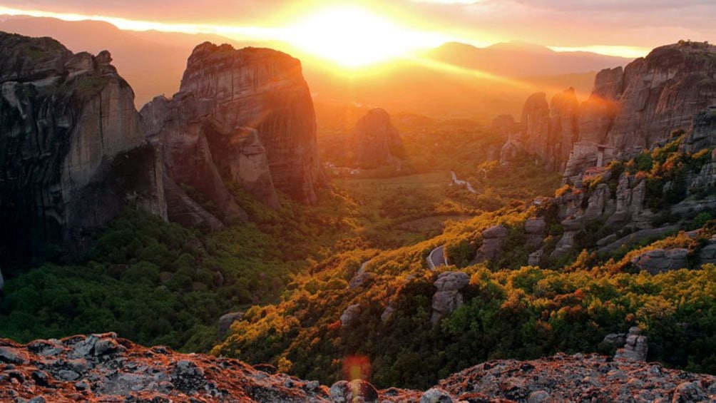 sun setting into the mountainous horizon in Athens