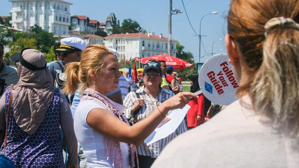 Tourists observing tour guide outdoors.