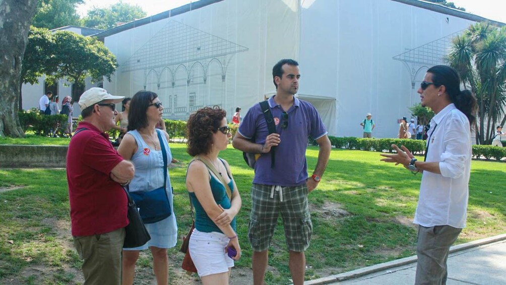 Tourists observing tour guide outdoors.