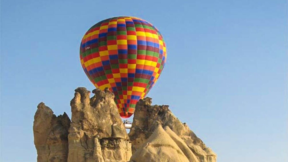Hot air balloon lifting off behind canyon.