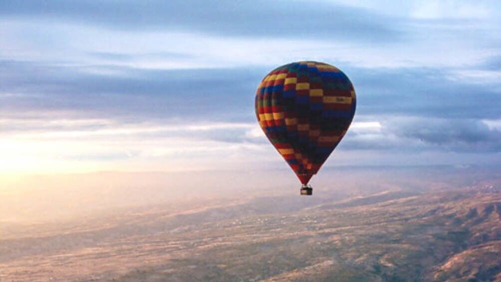 Hot air balloon floating over city at sunset.