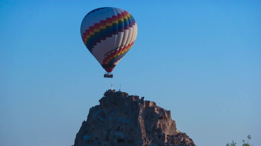 Hot air balloon ascending over canyon.