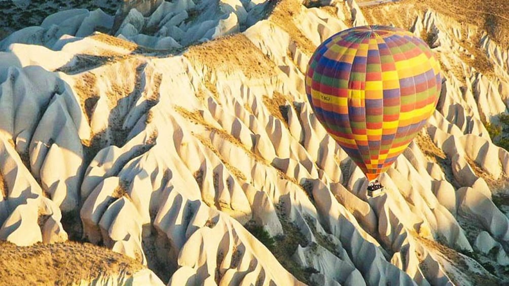 Hot air balloon floating over canyon.