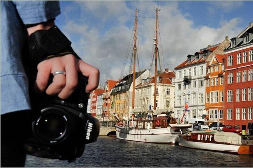 A photographer holding a Nikon SLR whilst overlooking the popular tourist district of Nyhavn