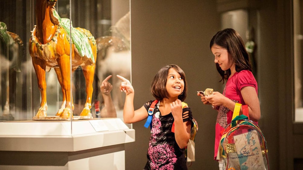 Two children observing displayed art at museum.