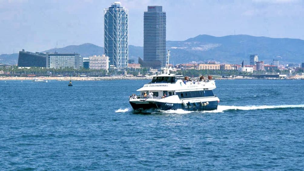 boat cruising near skyscrapers in Barcelona