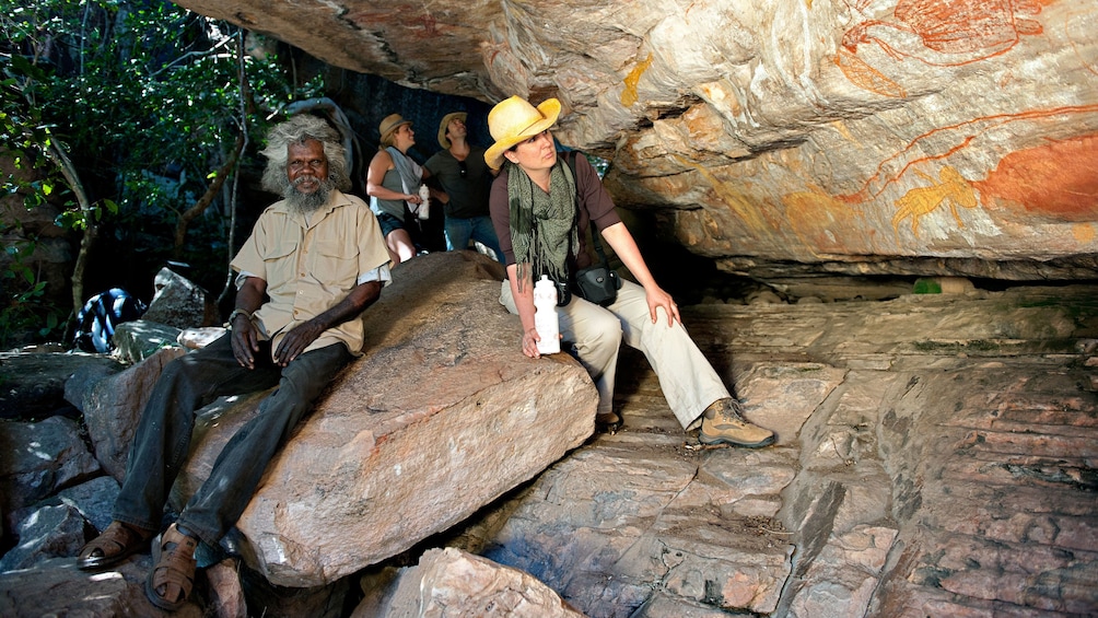 Show item 1 of 5. Tour group looking at rocks with ancient drawings