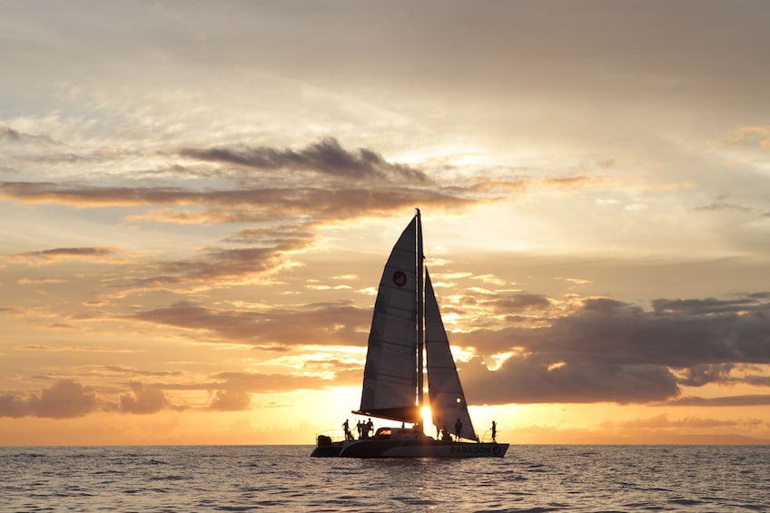 Show item 4 of 7. Catamaran sailing past sunset off of Maui
