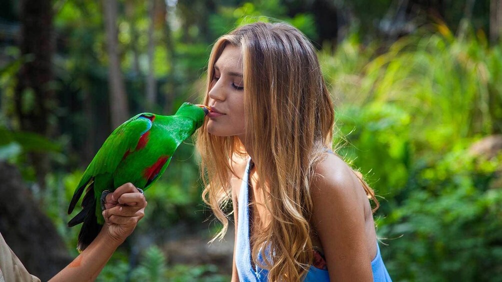 woman kissing a green bird at the zoo in Bali